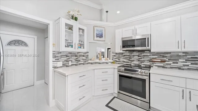a kitchen with granite countertop white cabinets stainless steel appliances and a counter space