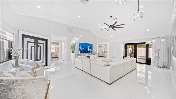 a living room with furniture a ceiling fan a flat screen tv and a large window