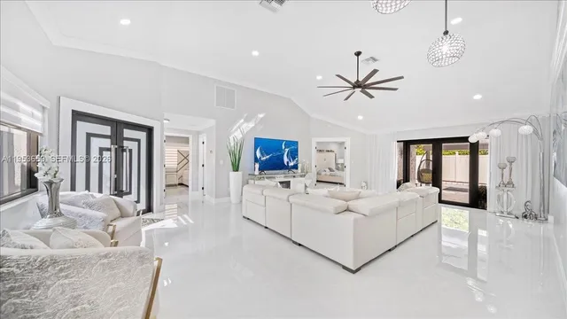 a living room with furniture a ceiling fan a flat screen tv and a large window