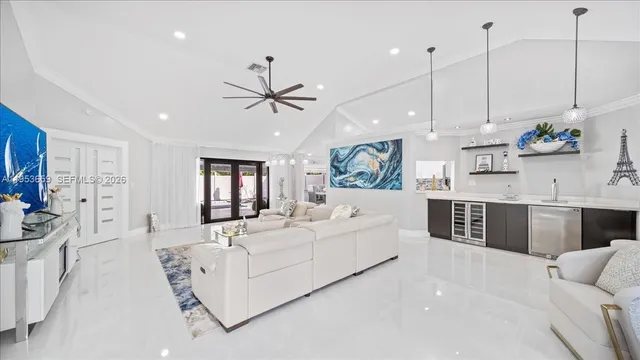 a large white kitchen with stainless steel appliances granite countertop a stove a sink a living room with couches and furniture