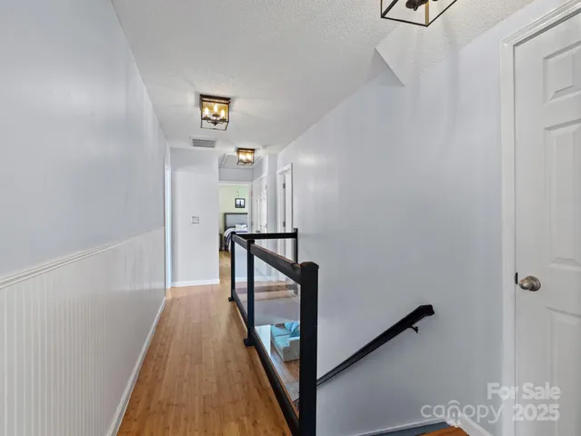 a view of a hallway with wooden floor and staircase