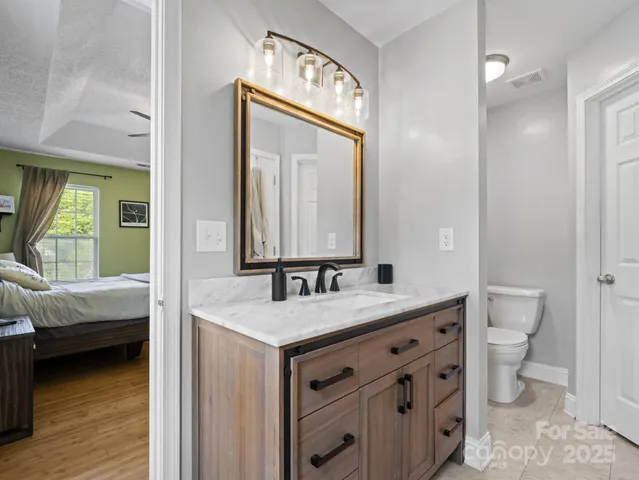 a en suite bathroom with a granite countertop sink and a mirror