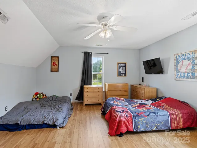 a bedroom with a large bed and a flat tv screen on dresser