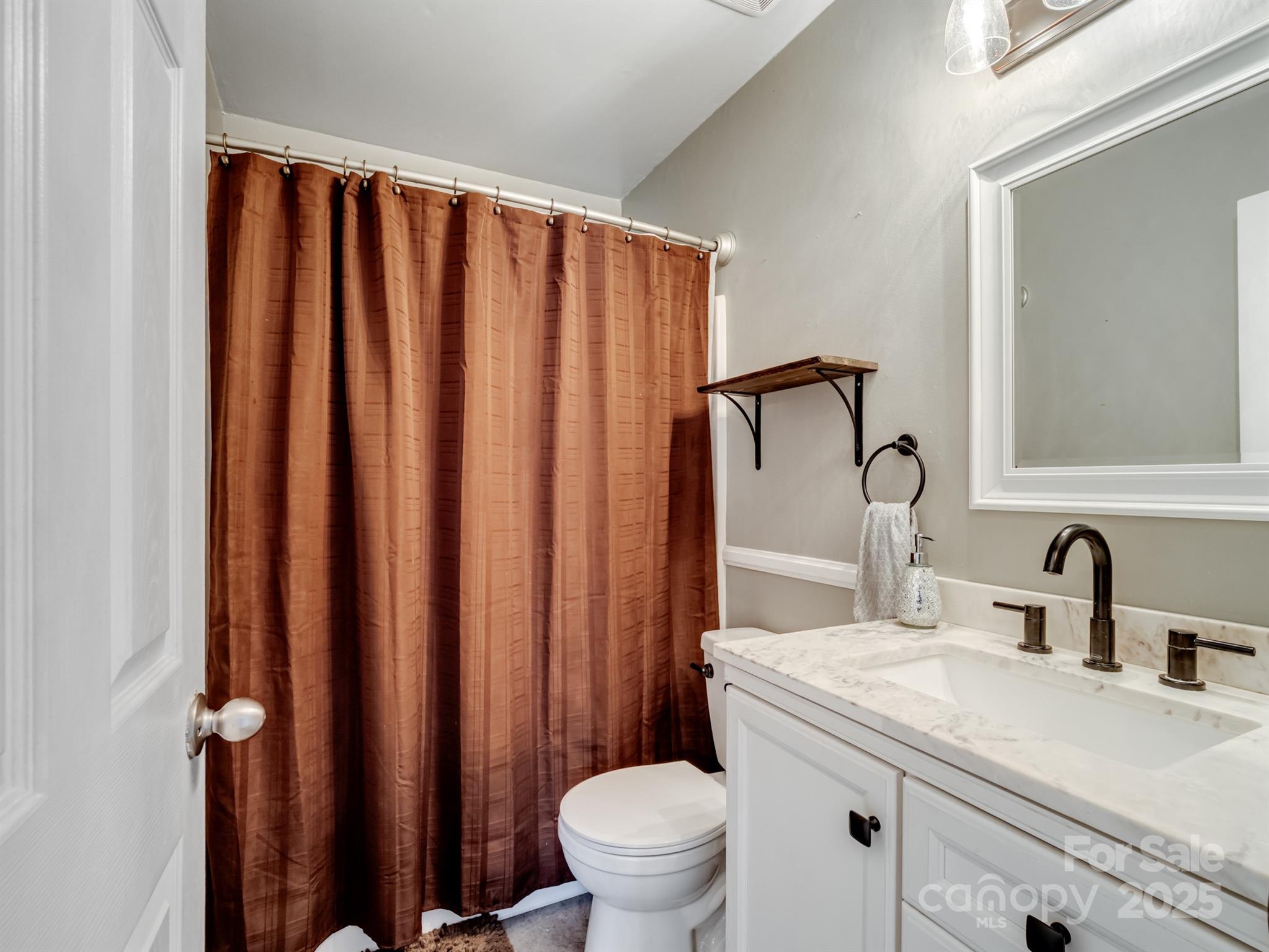 5535 Whispering Wind Lane Indian Trail, NC 28079 - Photo 21 of 25 a bathroom with a sink a toilet and a mirror