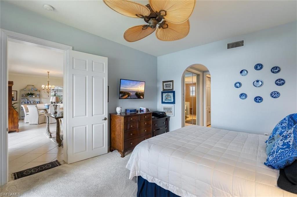 821 Regency Reserve Circle, Unit 3802 Naples, FL 34119 - Photo 15 of 26 a bedroom with a bed and a chandelier