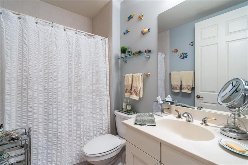 821 Regency Reserve Circle, Unit 3802 Naples, FL 34119 - Photo 18 of 26 a bathroom with a sink a toilet and shower curtain