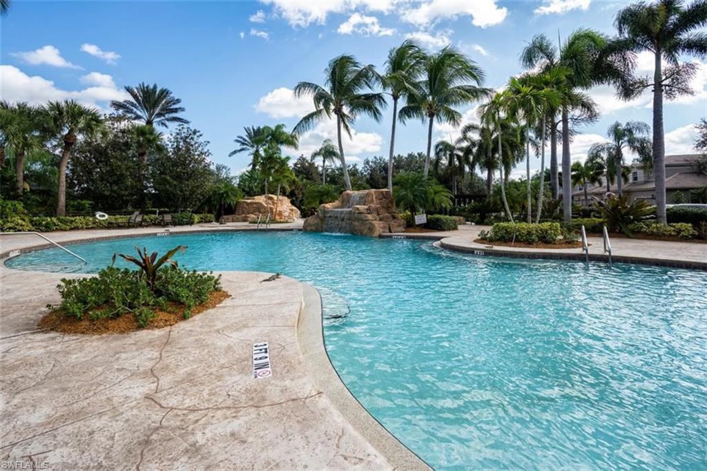 821 Regency Reserve Circle, Unit 3802 Naples, FL 34119 - Photo 23 of 26 a view of a swimming pool with a lawn chairs and palm trees