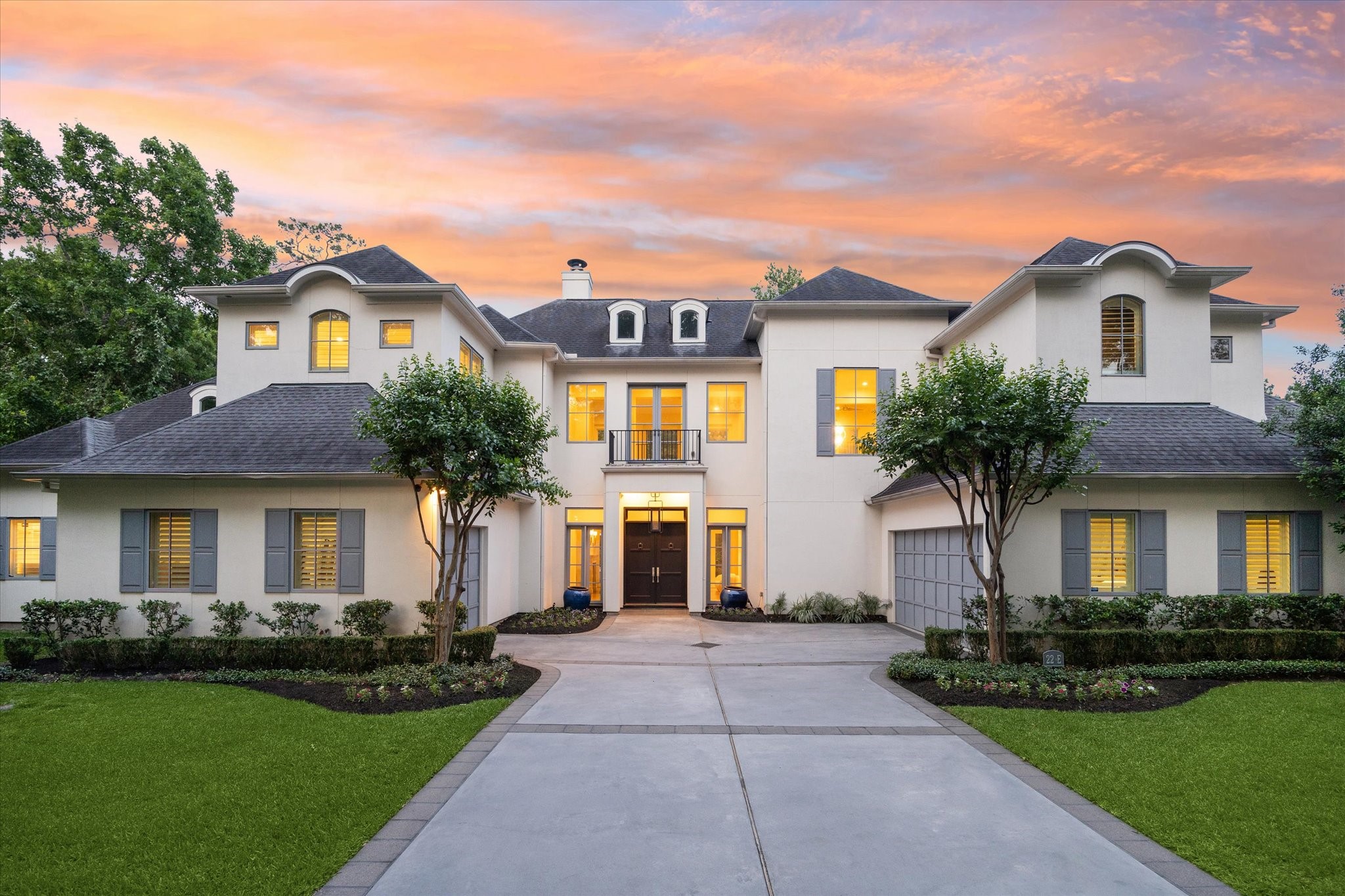 This stunning two-story home at 22 E Shade Lane boasts a grand entrance with elegant architecture. The property features a well-manicured lawn, symmetrical landscaping, and warm exterior lighting that highlights its beauty