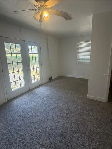 an empty room with windows and chandelier fan