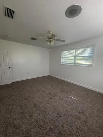 an empty room with a ceiling fan and window