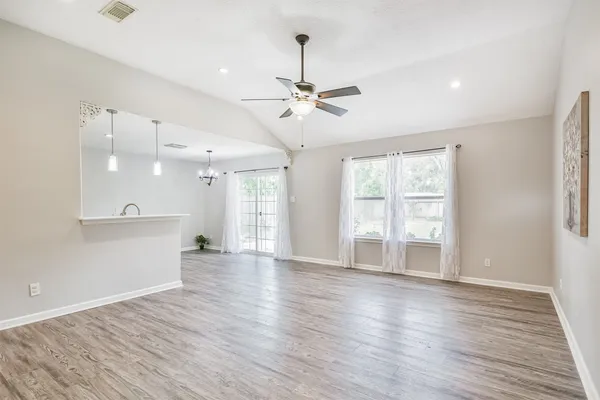 a view of an empty room with window and wooden floor
