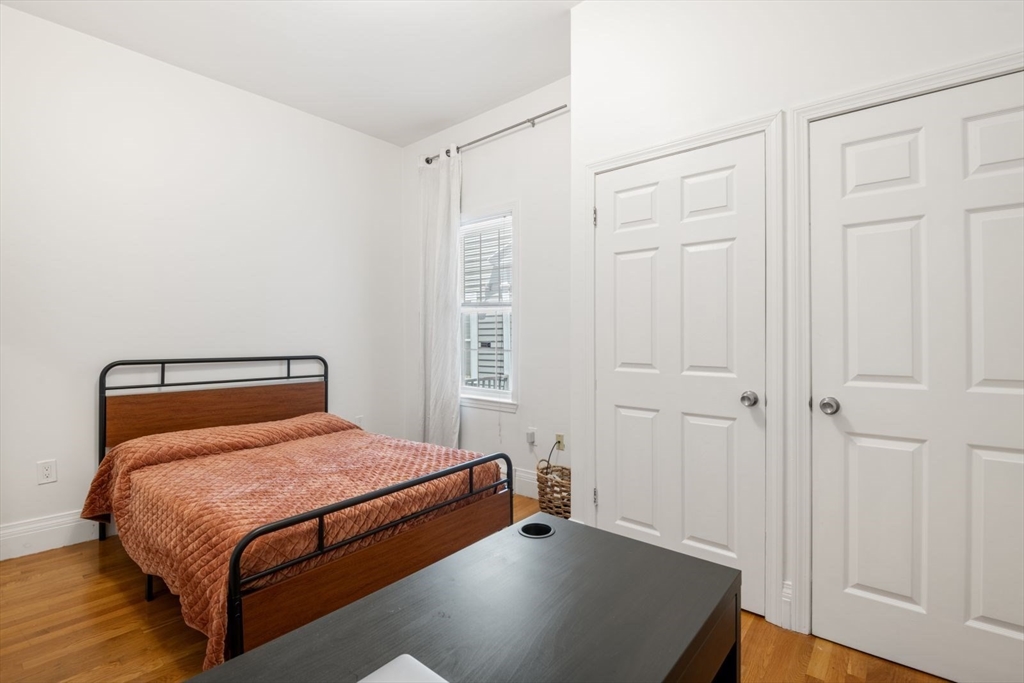 249 Roxbury Street, Unit 1 Boston, MA 02119 - Photo 13 of 19 a bedroom with a bed and wooden floor