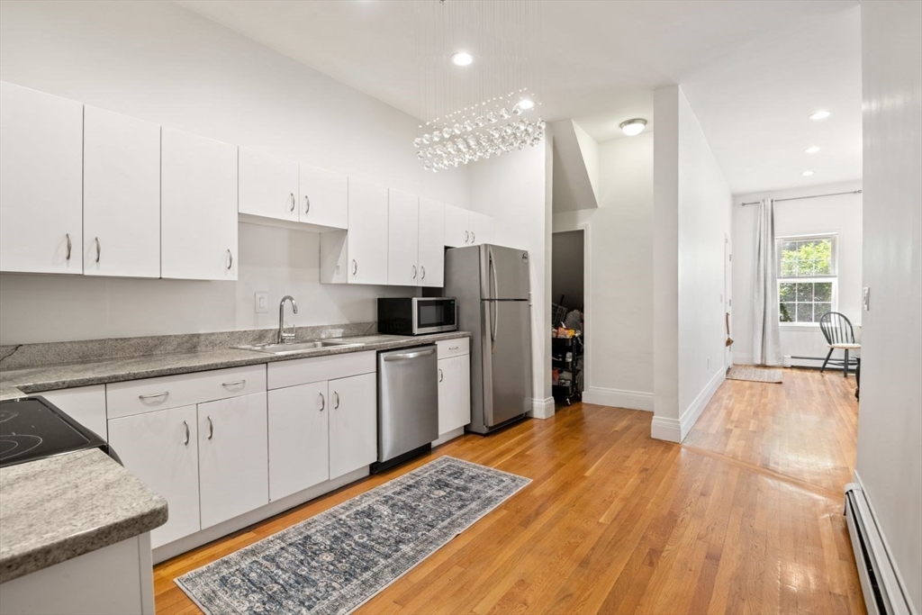 249 Roxbury Street, Unit 1 Boston, MA 02119 - Photo 8 of 19 a kitchen with stainless steel appliances granite countertop a refrigerator and a stove top oven