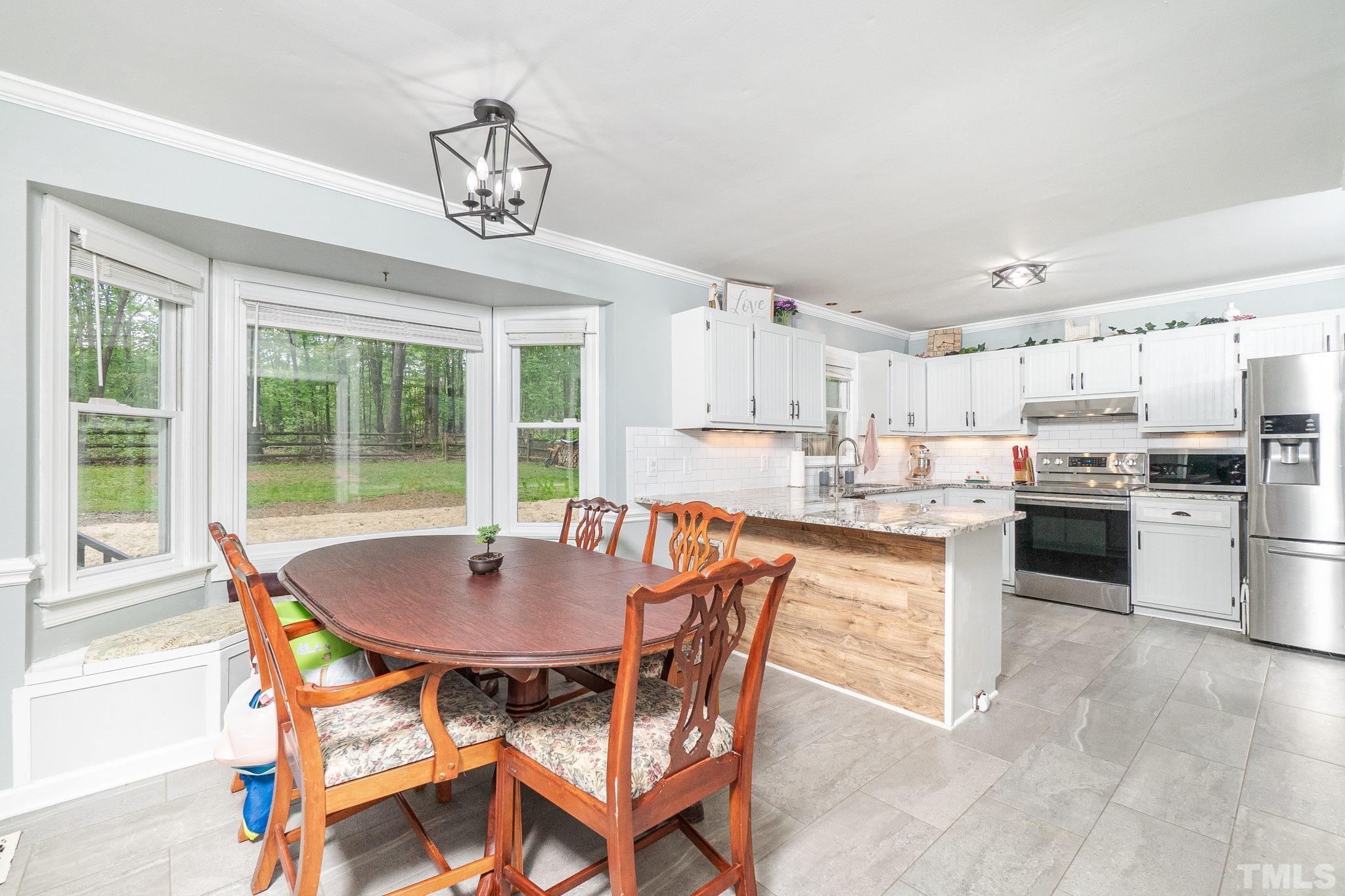 6313 Craig Road Durham, NC 27712 - Photo 17 of 38 a kitchen with a dining table chairs and refrigerator