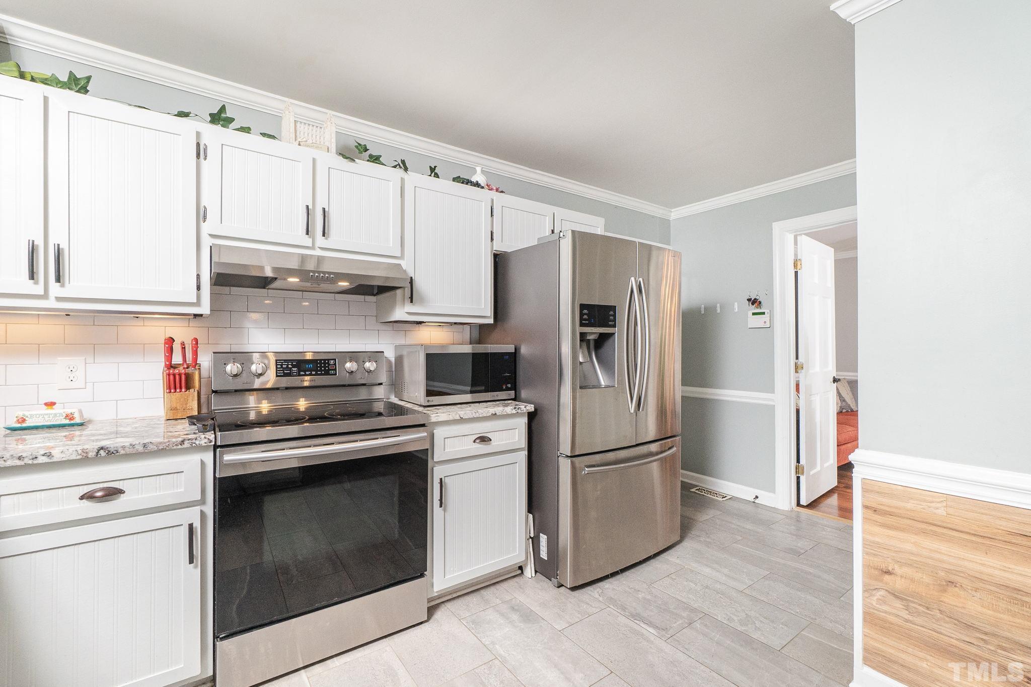 6313 Craig Road Durham, NC 27712 - Photo 22 of 38 a kitchen with cabinets stainless steel appliances and wooden floor