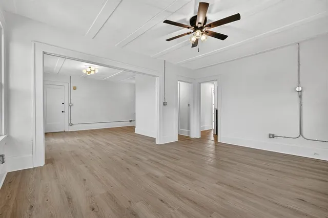 an empty room with wooden floor and a ceiling fan
