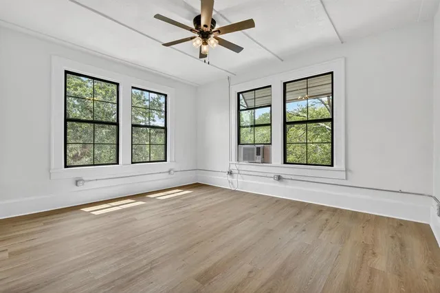 an empty room with wooden floor and windows