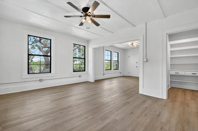 a view of an empty room with a window and wooden floor