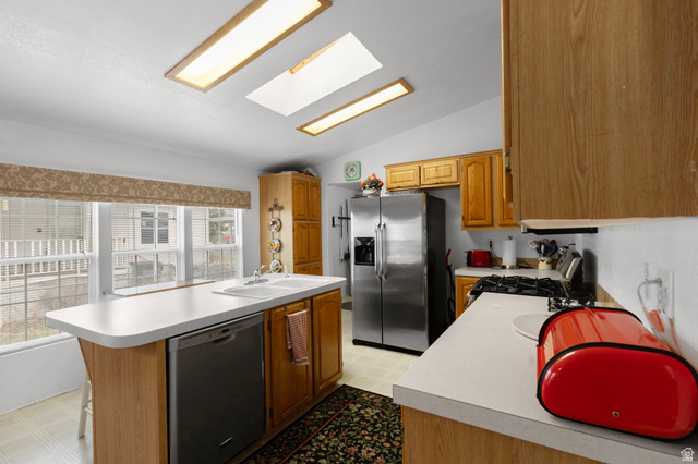 2600 North Hill Field Road, Unit 134 Layton, UT 84041 - Photo 11 of 41 Kitchen with a skylight, light flooring, stainless steel appliances, vaulted ceiling, and light countertops