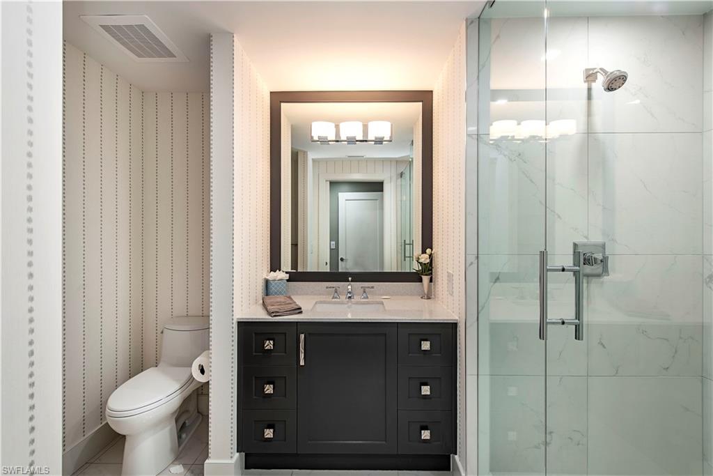 13915 Old Coast Road, Unit 302 Naples, FL 34110 - Photo 11 of 40 a bathroom with a toilet sink vanity and mirror