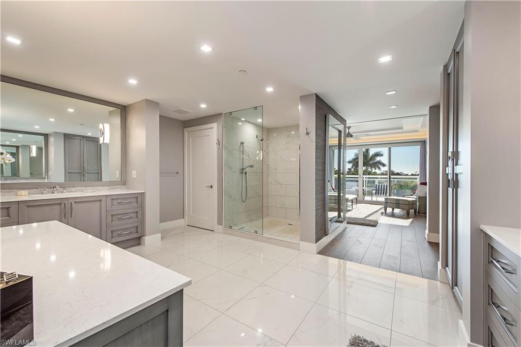 13915 Old Coast Road, Unit 302 Naples, FL 34110 - Photo 9 of 40 a bathroom with a sink a large mirror and shower