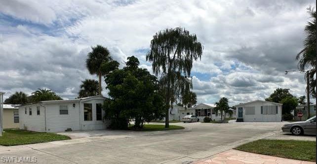 186 Panther Pass Circle, Unit 186 Naples, FL 34114 - Photo 38 of 50 a view of a white house with a yard and table and chairs under an umbrella