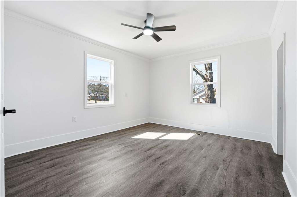 34 Wade Street Winder, GA 30680 - Photo 16 of 22 an empty room with wooden floor ceiling fan and windows
