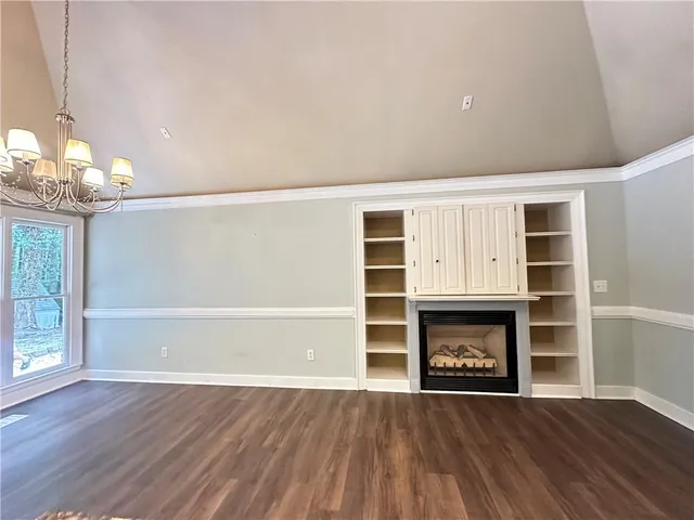 a view of an empty room with wooden floor fireplace and a window
