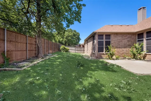 a view of a brick house with a big yard and large trees