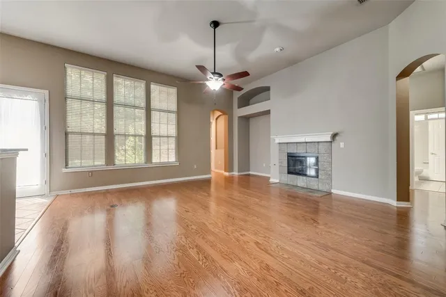 an empty room with wooden floor fireplace and windows