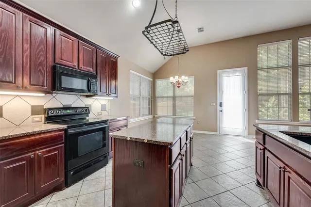 a kitchen with granite countertop stainless steel appliances a stove sink and cabinets