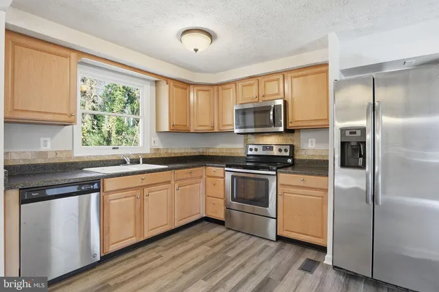a kitchen with stainless steel appliances granite countertop a stove a sink dishwasher a refrigerator and a microwave