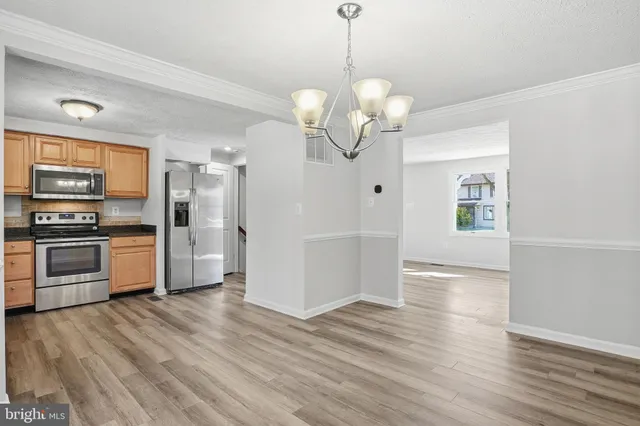 a view of a kitchen with wooden floor and stainless steel appliances