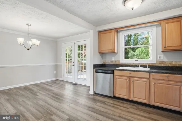 a kitchen with granite countertop a stove a sink and white cabinets with wooden floor