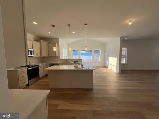 a large kitchen with stainless steel appliances kitchen island a large counter top and a wooden floors