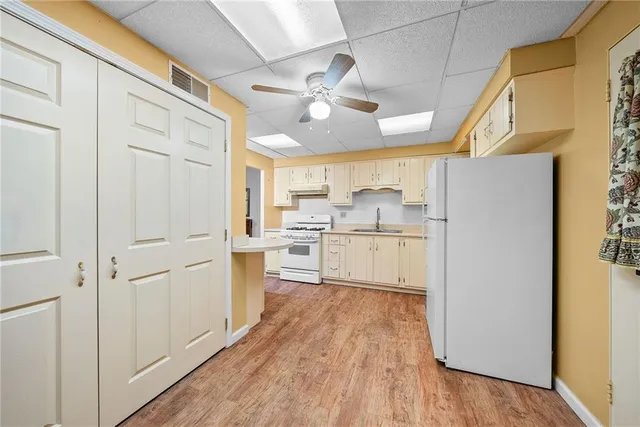 a kitchen with white cabinets and wooden floor