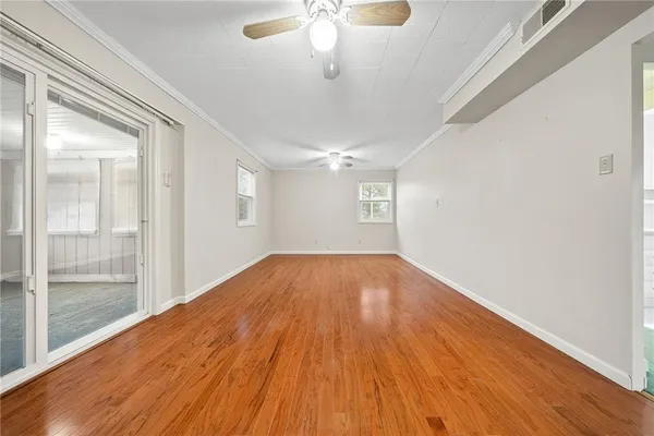 a view of empty room with wooden floor and fan