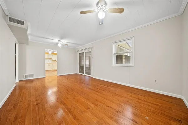 a view of empty room with wooden floor and fan
