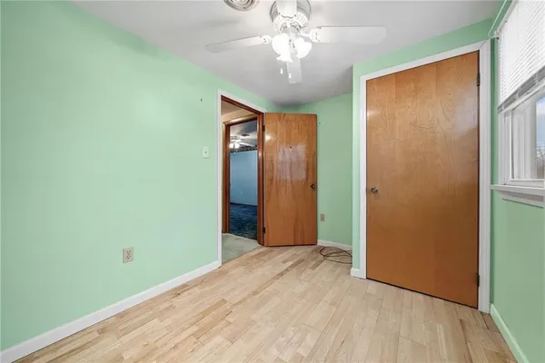 wooden floor in an empty room with a chandelier fan