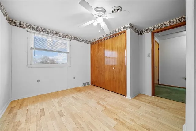 a view of empty room with wooden floor and fan