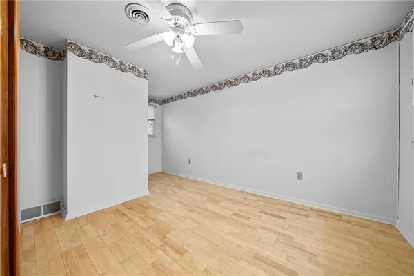 a view of a big room with carpet and a chandelier fan