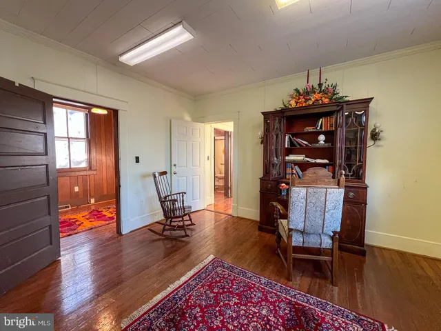 a view of a hallway with wooden floor and living room