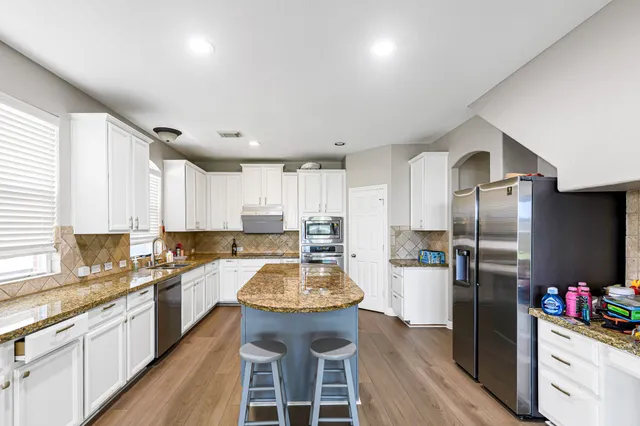 a kitchen with stainless steel appliances granite countertop a refrigerator a stove and a wooden floors