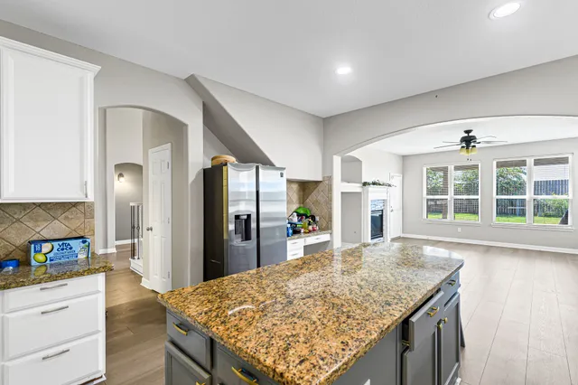 a large kitchen with kitchen island a sink granite counter tops and a large window