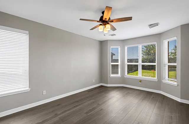 a view of an empty room with wooden floor and a window