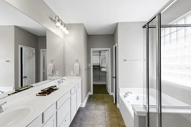 a bathroom with a double vanity sink a mirror and a bathtub