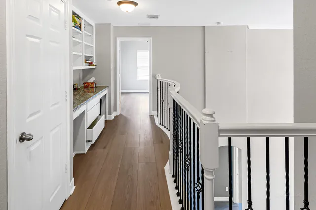 a view of a hallway with wooden floor and staircase