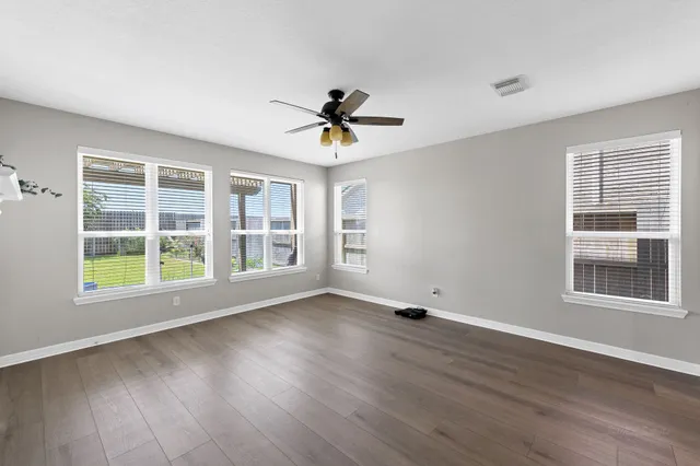 a view of an empty room with a window and wooden floor