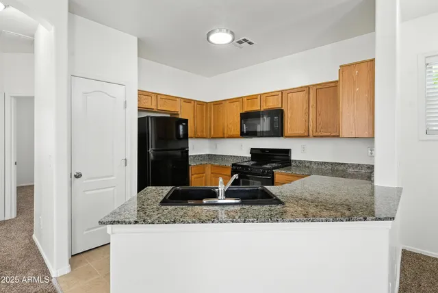 a kitchen with granite countertop a refrigerator a stove and a sink