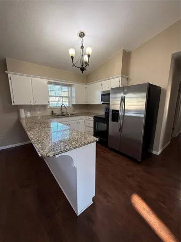 a large kitchen with a center island wooden floor and stainless steel appliances